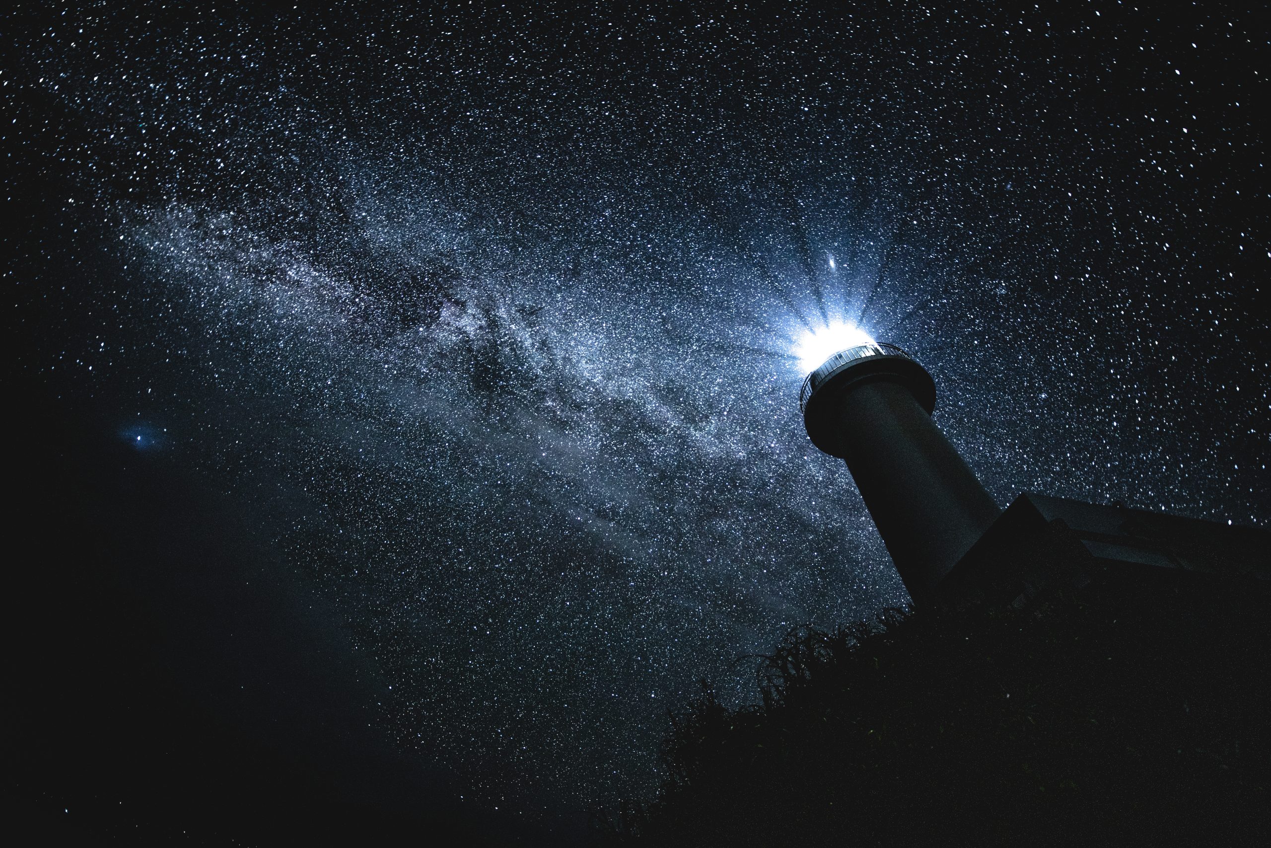 Photograph of a lighthouse on a dark night with Milky Way in the background